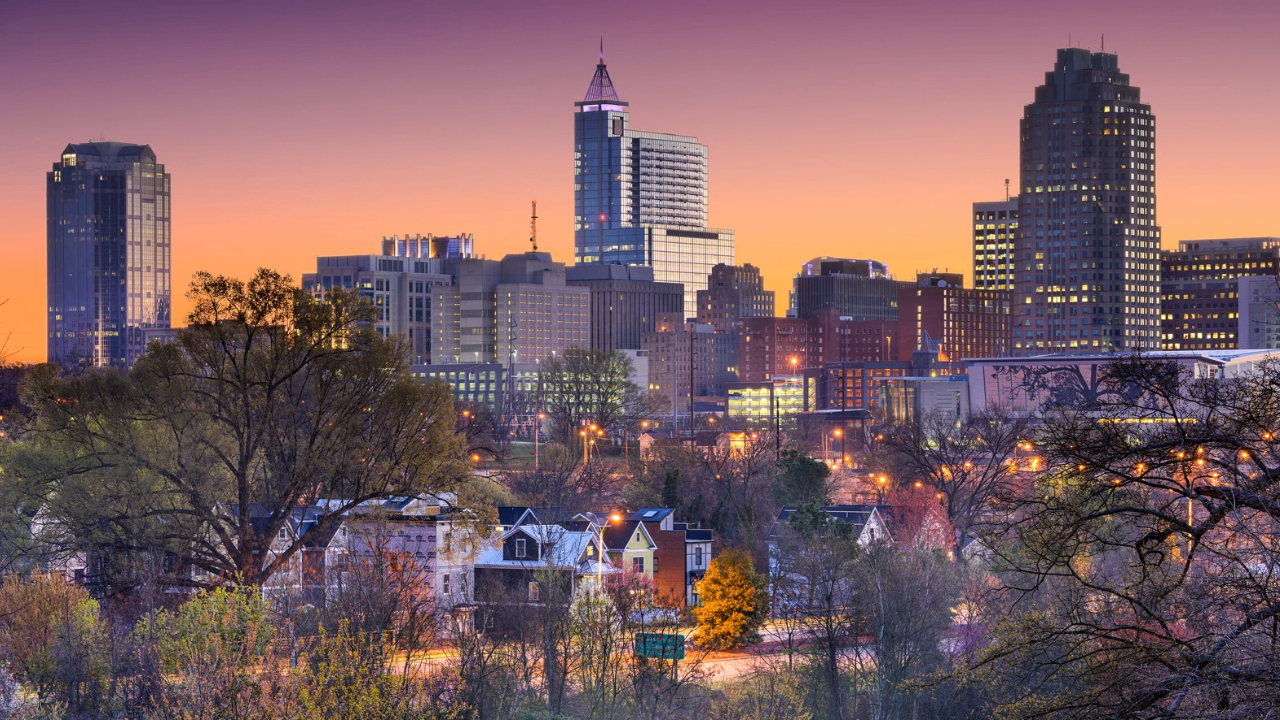 Downtown Raleigh skyline at sunset above the tree line
